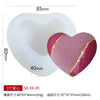 A pink heart-shaped silicone mold with gold accents shown next to its white base.