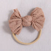 A light beige knitted fabric bow headband with a soft elastic band.