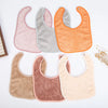 A collection of soft cotton baby bibs in various pastel and earthy tones, including pink, gray, orange, and brown.