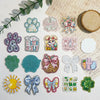 A collection of 10 glitter acrylic flatback resin cabochons featuring paw prints, Easter themes, and various floral shapes.