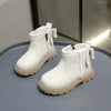A pair of white cozy kids winter boots with faux leather finish displayed on a gray surface.