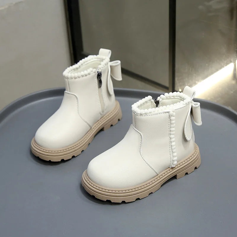A pair of white cozy kids winter boots with faux leather finish displayed on a gray surface.