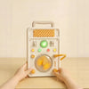A hand is operating an interactive circuit busy board with lights and switches on a wooden table.