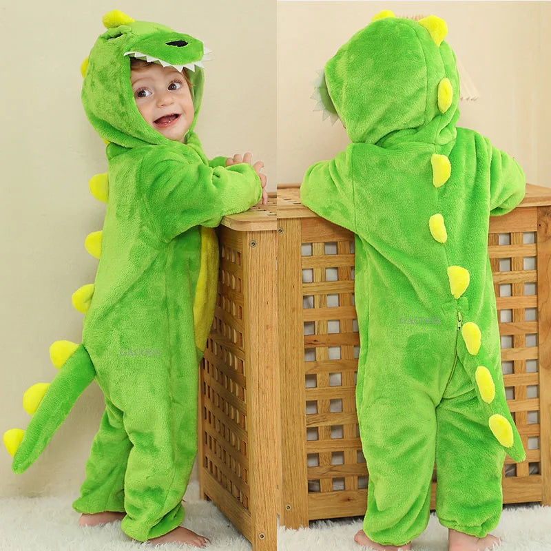 A happy baby wearing a bright green animal hooded romper with yellow accents standing in front of a wooden crib.