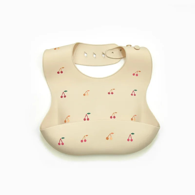 A beige soft silicone waterproof baby bib with an adjustable neck and small fruit graphics.