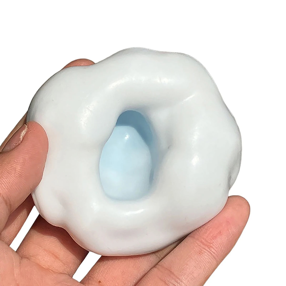 A hand holds a white, squishy stress ball with a blue center, used as a sensory fidget toy.
