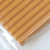 A close-up view of a rectangular block of soft, yellowish-orange polymer clay modeling material.