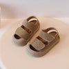 A pair of tan soft-soled sandals for toddlers, shown from above on a light surface.