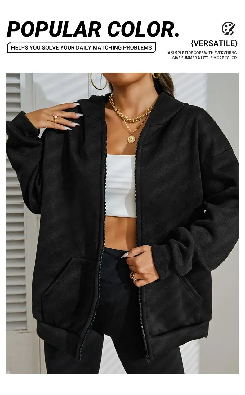 A model wears a black oversized zip-up hoodie over a white top and dark pants.