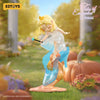 A blonde elf figure with a blue wand stands in a garden setting surrounded by pumpkins and flowers.