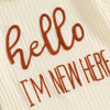 A close-up of a cream ribbed garment featuring hand-stitched brown text that reads Hello I'm new here