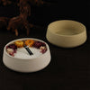 A white silicone mold containing dried floral elements on a dark wooden surface next to a light beige bowl.