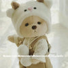 A fluffy white teddy bear plush wearing a beige dress and hat.