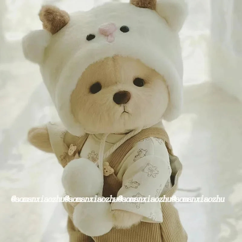 A fluffy white teddy bear plush wearing a beige dress and hat.