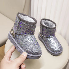 A pair of purple glitter winter snow boots with faux fur lining resting on a light surface.