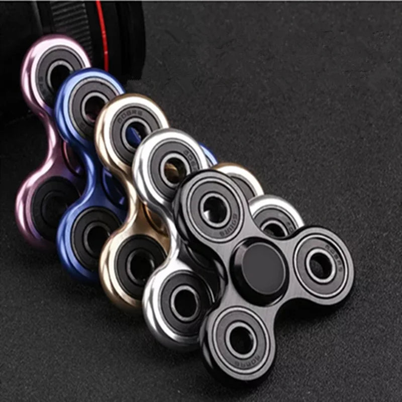 A collection of colorful aluminum alloy fidget spinners arranged in a line against a dark background.