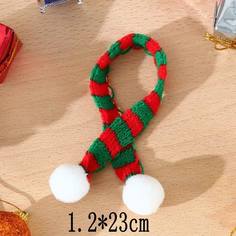 A knitted green and red accessory featuring a loop and two white pom-poms for doll dress-up.