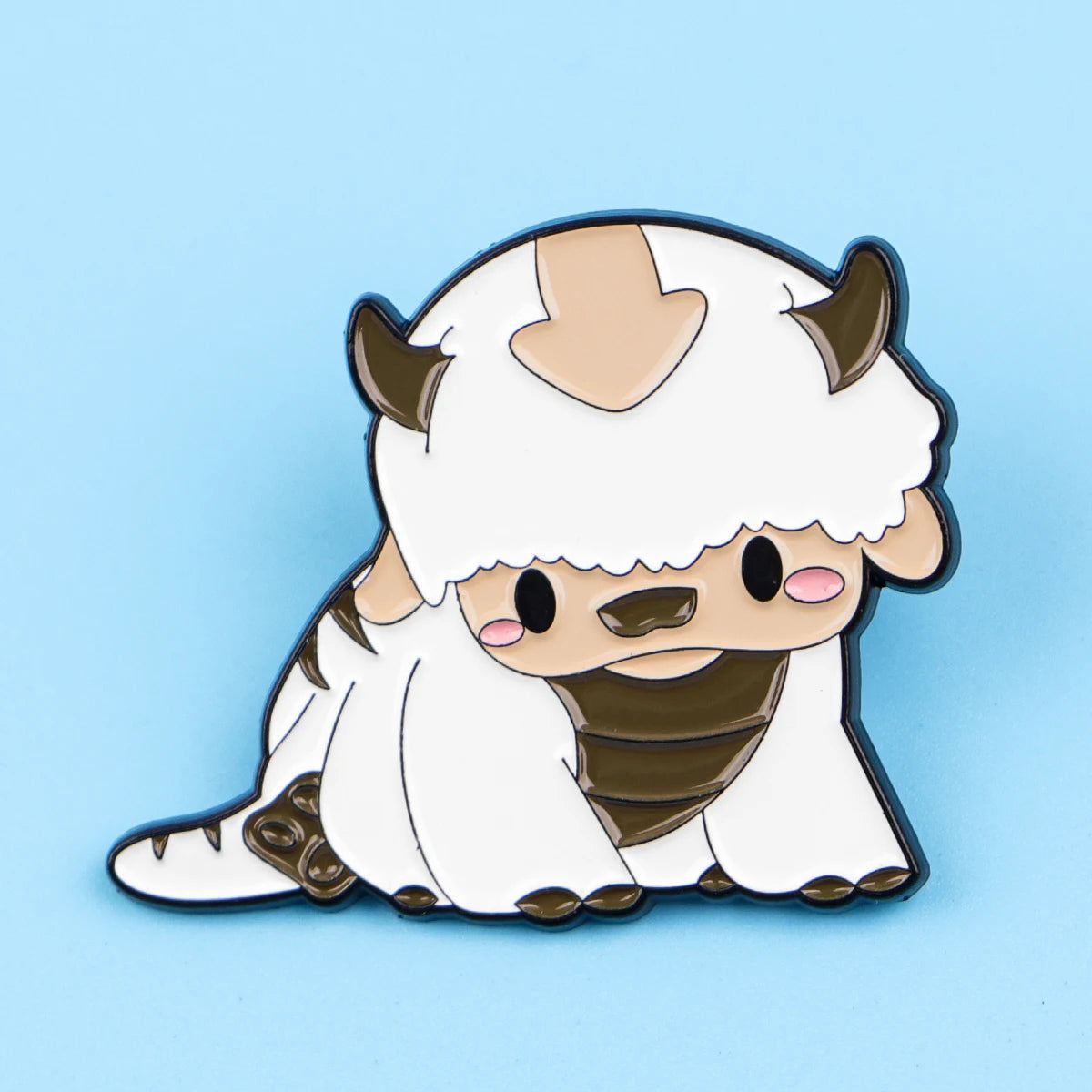 A cute enamel pin featuring a white, fluffy creature with horns and brown accents.
