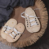 A pair of light wooden lacing shoes with white laces resting on a woven jute mat.