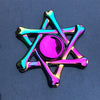 A shiny, iridescent rainbow metal fidget spinner with a central purple sphere.