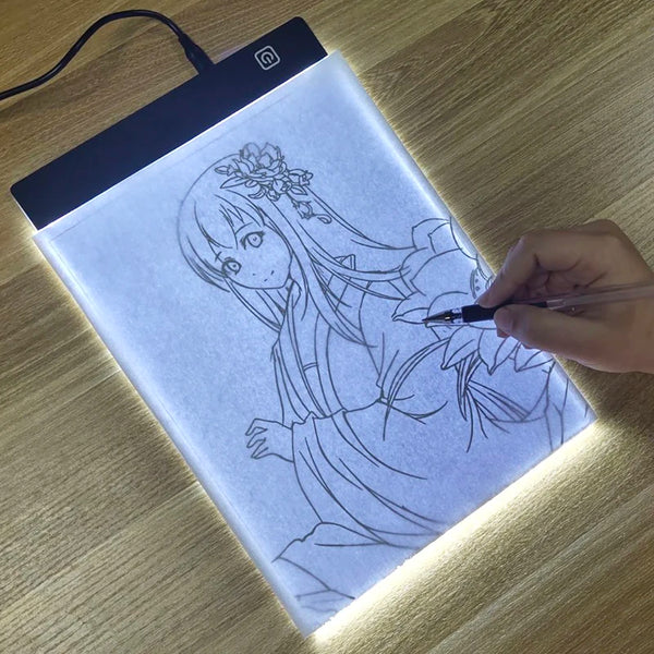 Una mano dibuja una chica en detalle con lápiz sobre una tableta LED iluminada.