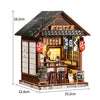 A miniature Japanese-style wooden shop or book nook featuring a tiled roof, wooden facade, and illuminated display.