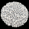 A close-up view of small white acrylic alphabet letter beads scattered on a dark background.