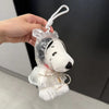 A white Snoopy plush keychain charm is being held by a hand against a dark background.