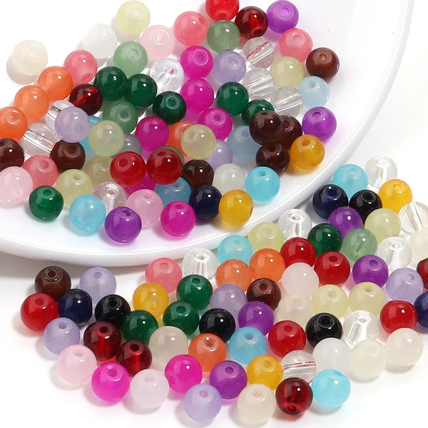 A collection of round glass spacer beads in various colors including red, green, purple, yellow, and clear shades.