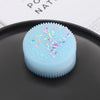 A light blue biscuit squishy stress relief toy with colorful sprinkles resting on a dark gray plate.