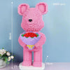 A pink flower bear figure made of tiny pink building blocks standing on a white base.