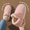 A pair of pink faux fur slippers being held, showing the plush interior and exterior texture.
