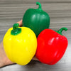 A hand holds a yellow and a red squishy bell pepper fidget toy for stress relief.