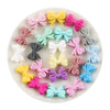 A collection of colorful silicone bow tie beads in various shades including pink, yellow, purple, and blue arranged on a whit