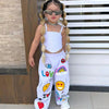 A girl wearing a white two-piece outfit with a suspender top and long pants, accessorized with sunglasses and jewelry.