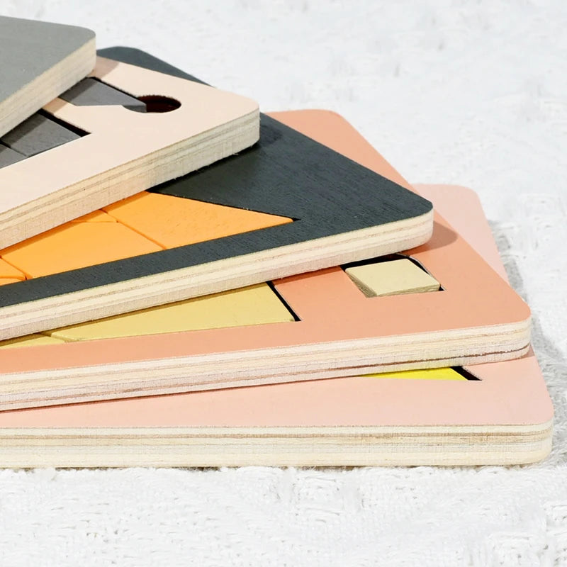 A stack of wooden geometric brain teaser puzzles in various colors like orange, yellow, and pink.