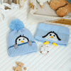 A knitted blue penguin hat and scarf set with white accents resting on a white surface.