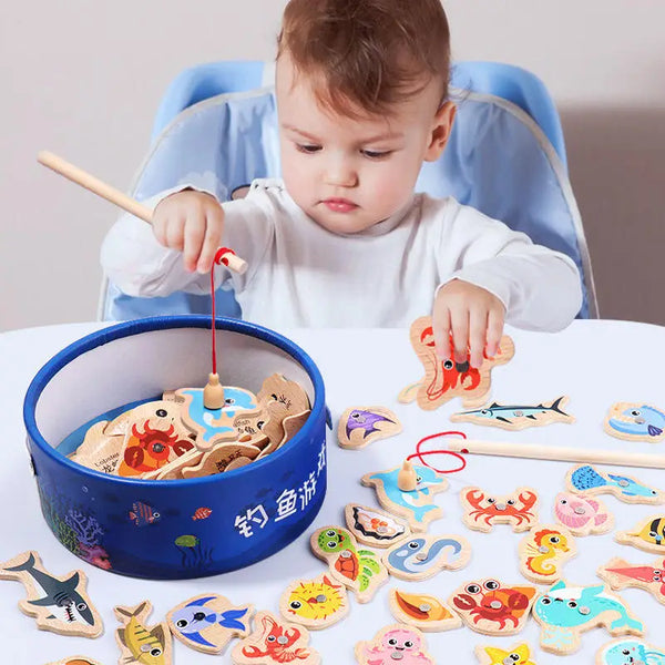 A child is playing with wooden magnetic fishing toys in a blue bowl on a white table.