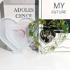 A silicone mold shaped like a heart is displayed in front of books titled Adolescence and My Future.