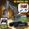 A gray remote control excavator model with a green body and tracks is shown on sand, next to its battery and controller.