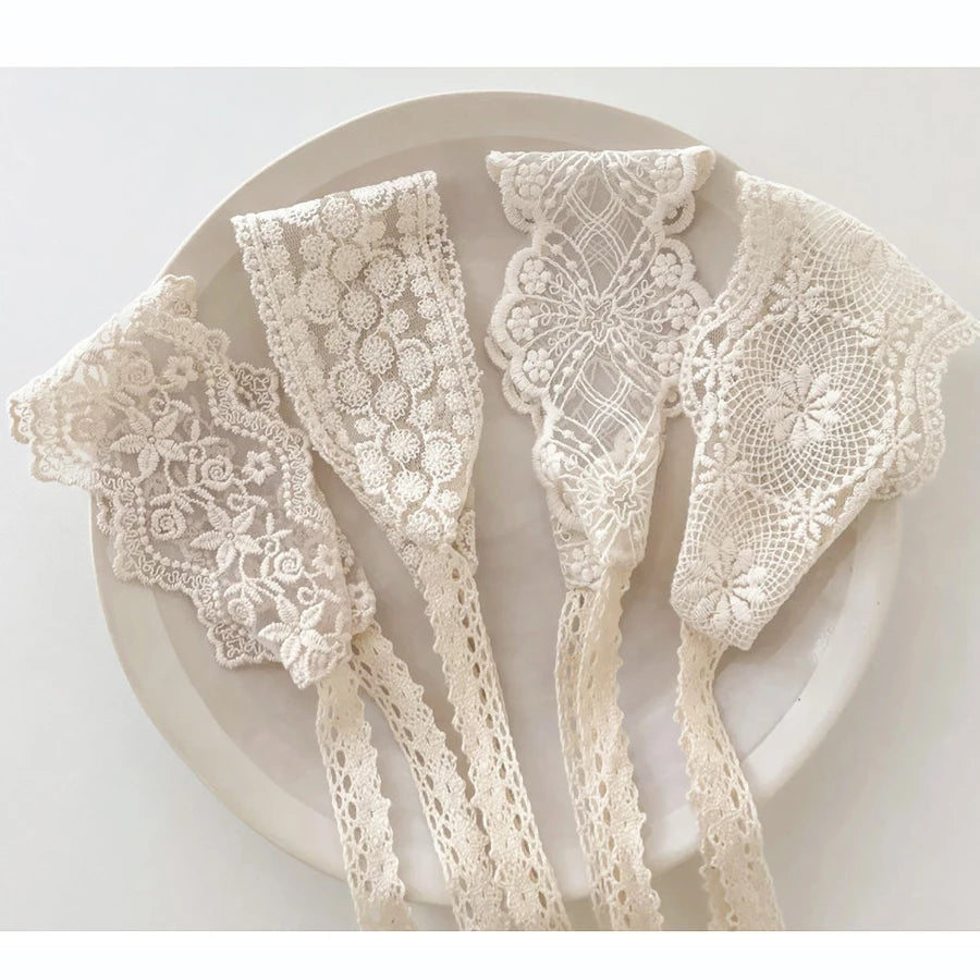 A collection of white floral lace baby headbands for newborns displayed on a light-colored plate.