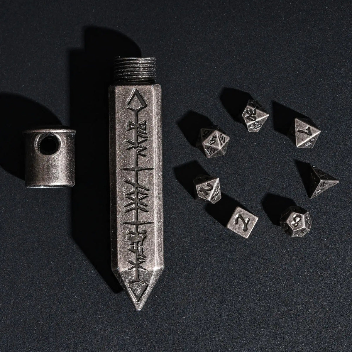 A silver metal dice set with a bullet box is displayed on a dark surface.