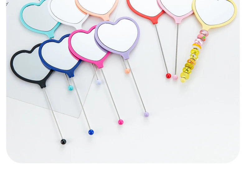 A collection of beaded hand mirrors shaped like hearts in various colors and designs