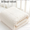 A stack of white 3D bean velvet blankets folded on a white surface.