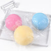 Three colorful squishy toys, pink, blue, and yellow, are packaged in clear plastic on a white tray.