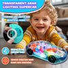 A smiling toddler is holding a transparent gear car with lights and music, demonstrating its bump-and-go feature.