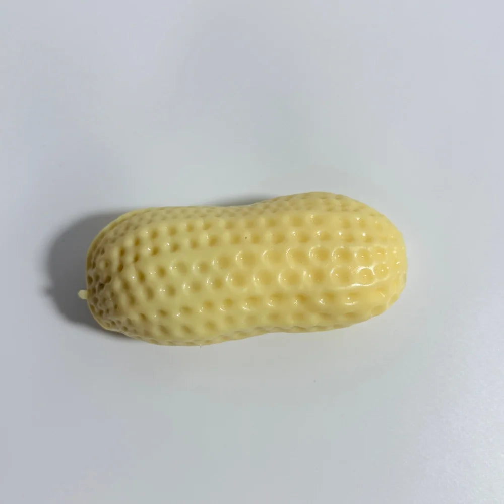 A light yellow, elongated peanut-shaped squishy stress ball with a textured surface.