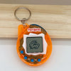 An orange electronic pet game toy with a screen and buttons is displayed on a wooden surface.