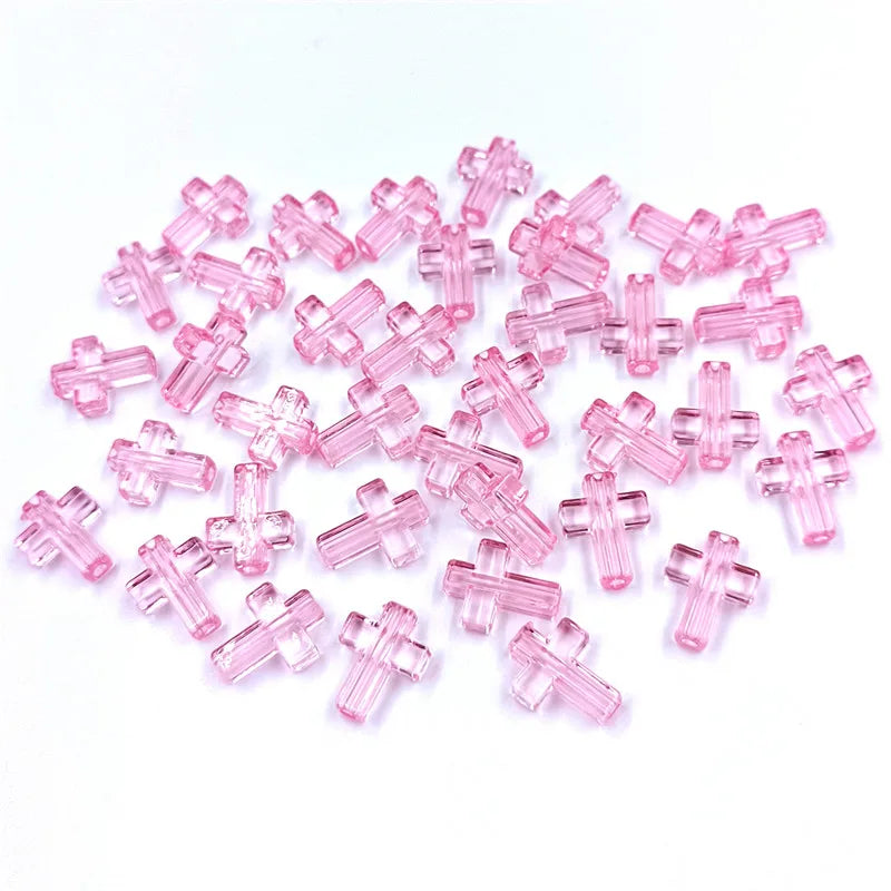 A pile of small, pink acrylic cross beads for jewelry making.