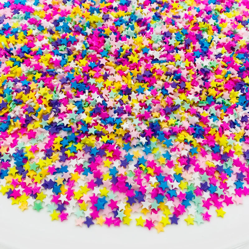 A close-up of colorful polymer clay star and heart sprinkles scattered on a white surface.
